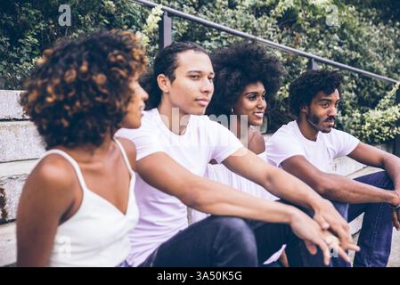 Groupe d'amis divers profitant du temps ensemble à New York, en plein air dans un parc près du paysage urbain. Une image de style de vie vivante qui capture l'amitié, le rire et la vie urbaine. Banque D'Images
