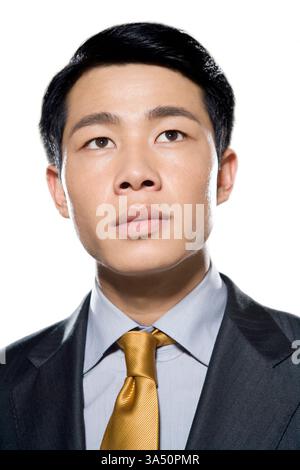 Portrait professionnel d'un homme d'affaires chinois sur un fond de studio blanc. Il regarde avec une expression confiante et ciblée, suggérant ambition et succès. Banque D'Images