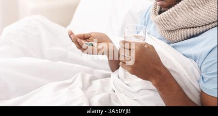 Un homme malade est assis dans son lit tenant de nombreuses pilules, illustrant un concept de soins de santé et de traitement. Cette image fonctionne bien pour les articles sur la maladie, la médecine et les soins aux patients. Banque D'Images