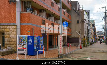 Osaka, Japon - 23 septembre 2024, vue panoramique d'une rue avec immeuble d'appartements en briques, distributeurs automatiques au coin de la rue, sans personnes, sur Banque D'Images