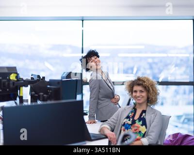 Groupe de jeunes femmes développeurs de logiciels collaborant dans un bureau de démarrage moderne. Ils codent sur les ordinateurs portables et de bureau, reflétant une équipe technique diversifiée dans un espace de travail créatif. Parfait pour les histoires sur les femmes dans la technologie, les startups et le travail d'équipe dans les logiciels et l'innovation. Banque D'Images