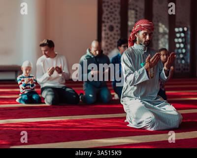 Un groupe de musulmans dans une mosquée moderne exécutent la prière Namaz pendant le Ramadan. La scène met l'accent sur la foi, la spiritualité et la communauté dans un espace de culte contemporain. Convient aux projets culturels, religieux et éducatifs. Banque D'Images