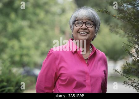 Portrait d'une femme afro-américaine plus âgée portant des lunettes, souriant en levant les yeux. Cette image chaleureuse et édifiante met en valeur les personnes âgées et les portraits avec une ambiance pleine d'espoir. Tourné à Montclair, dans le New Jersey, il fonctionne bien pour une image de marque diversifiée et positive pour l'âge. Banque D'Images