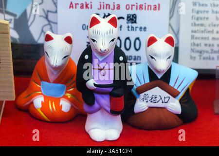 Kyoto, Japon - 23 septembre 2024, vue rapprochée de trois petites figures de renards kitsune blancs aux oreilles rouges vêtus de vêtements traditionnels japonais à un s. Banque D'Images