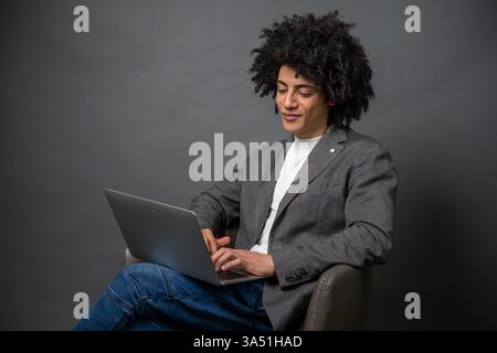 Jeune homme d'affaires noir concentré sur un ordinateur portable, regardant engagé dans son travail. Un portrait de style de vie professionnel adapté aux contextes d'entreprise. Banque D'Images