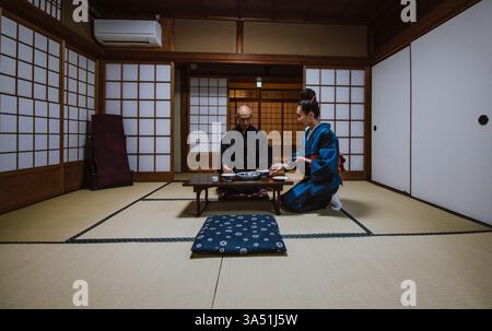 Couple japonais senior partagent un moment de calme à l'intérieur d'une maison traditionnelle portant un kimono. Cette scène sereine met en valeur le patrimoine, la compagnie et le mode de vie de retraite. Banque D'Images