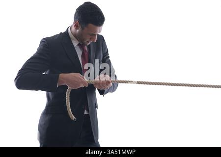 Homme d'affaires pensif du moyen-Orient tirant une corde dans un cadre de studio. Cette image exprime l'effort, le défi et l'ambition de l'entreprise, adapté aux affaires, la motivation, et des thèmes de leadership. Banque D'Images