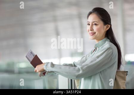 Femme chinoise mature attendant à l'aéroport Banque D'Images