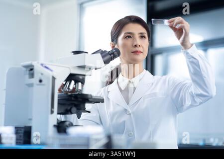 Un scientifique chinois examine une lame de microscope dans un laboratoire. Une image scientifique professionnelle adaptée à la biotechnologie, aux soins de santé et aux communications de recherche. Banque D'Images