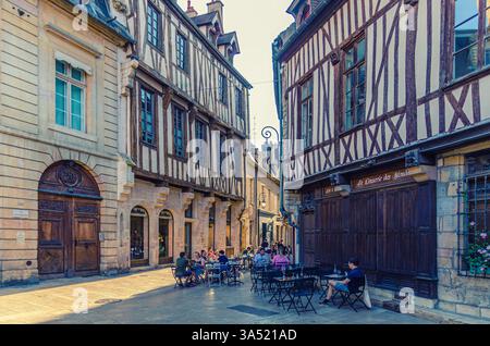 Dijon, France, 9 juillet 2024 : les gens assis rue restaurant café près des bâtiments médiévaux avec façade fachwerk dans la vieille ville de Dijon centre historique Banque D'Images