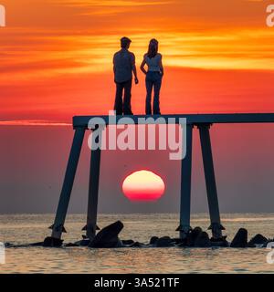 Vue à l'aube de la sculpture ''couple' sur le brise-lames à Newbiggin-by-the-Sea dans le Northumberland regardant vers la mer lorsque le soleil se lève Banque D'Images