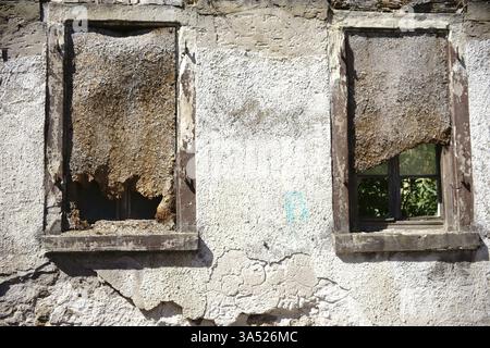 Deux fenêtres surmontées d'une ruine en danger de s'effondrer Banque D'Images