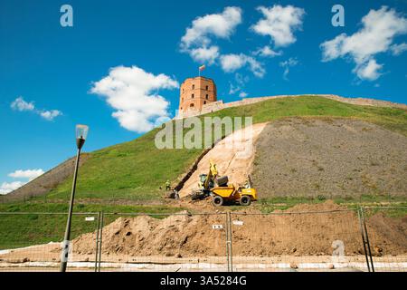 Ouvriers dans camion et excavatrice réparant les dommages causés par un glissement de terrain sur la colline de Gediminas avec le château au sommet dans la ville de Vilnius, Lituanie Banque D'Images