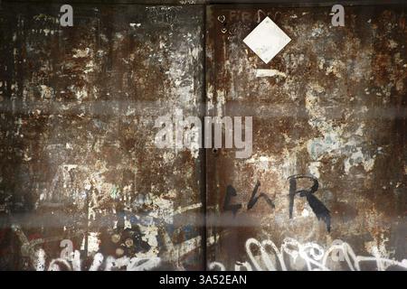 Une porte en fer fortement rouillée avec des griffonnages et des dommages Banque D'Images