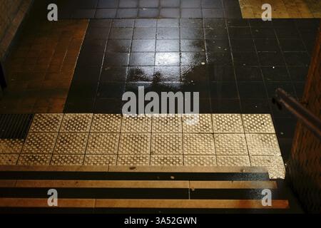 Les marches sombres d'un tunnel de gare avec des flaques d'eau et des murs humides Banque D'Images
