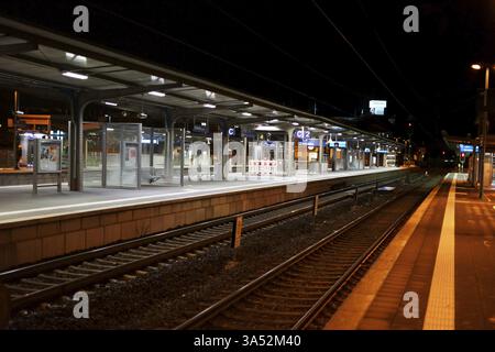 La plate-forme de la gare de Weinheim la nuit avec des sièges, des rails et des abris en verre Banque D'Images