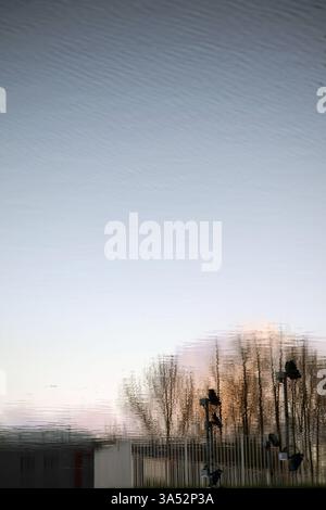 Arbres en automne reflétés dans un plan d'eau au coucher du soleil Banque D'Images