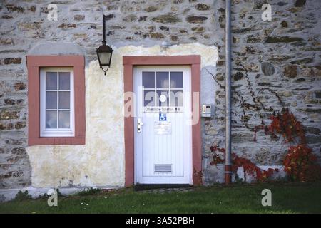 Une toilette publique dans une petite maison nostalgique avec une façade en pierre de champ et une lanterne Banque D'Images
