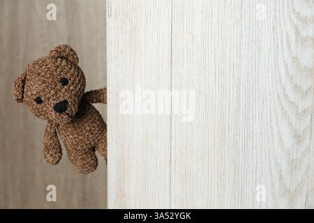 Ours jouet mignon jetant un coup d'œil hors de la planche de bois. Espace pour le texte Banque D'Images