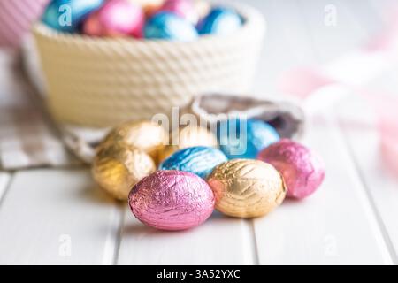 Oeufs de pâques en chocolat enveloppés dans une feuille multicolore sur une table blanche. Banque D'Images