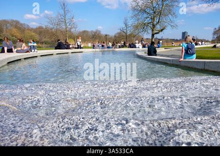 20 mars 2025, Londres, Royaume-Uni. Les températures de l'équinoxe de printemps ont atteint 21 °C alors que le Royaume-Uni enregistre le jour le plus chaud de l'année jusqu'à présent. Sur la photo : les gens se détendent le long de la Diana, Princess of Wales Memorial Fountain, sous le soleil du début du printemps, Hyde Park, Londres. Banque D'Images