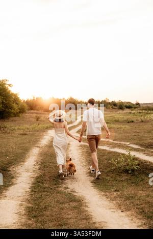 Un couple aimant profite d'une promenade romantique avec leur chien bien-aimé au cours d'un coucher de soleil à couper le souffle pittoresque, incarnant l'amour pur et le bonheur au milieu de natur Banque D'Images