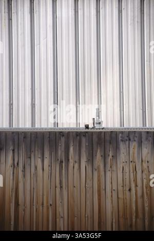 Barrière de chantier de construction et clôture de panneau devant la façade en fer ondulé d'un conteneur de construction Banque D'Images