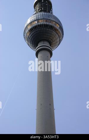 La vue d'en bas de la tour de télévision de Berlin contre un ciel bleu avec des stries de condensation Banque D'Images