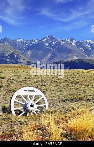 Panneau de signalisation routière en forme de roue de wagon. Route de gravier dans le désert. Au loin les montagnes enneigées. Patagonie Argentine, Perito Moreno Nati Banque D'Images