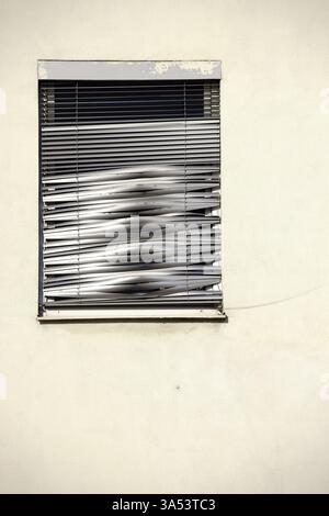 Gros plan d'une seule fenêtre avec un store métallique brisé brillant Banque D'Images