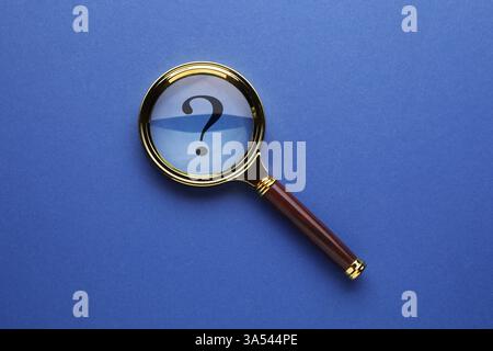 Point d'interrogation sur fond bleu, vue de dessus à travers la loupe Banque D'Images