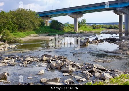 Gwangju, Corée du Sud - 24 septembre 2020 : un lit de rivière rocheux avec des rochers dispersés coule sous un pont de béton le long du Yeongsangang, entouré Banque D'Images