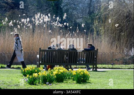 Londres, Royaume-Uni. Les gens assis à St James's Park un jour doux de mars Banque D'Images