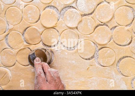 Couper des cercles de pâte un couteau rond en métal. Préparation de la pâte pour la cuisson, un gros morceau de pâte est sur la table et le chef coupe Banque D'Images