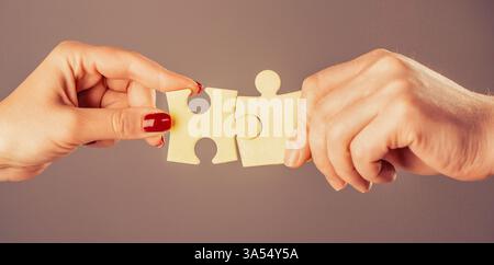 L'homme et la femme sont des pièces de liaison du puzzle. L'homme et la femme tiennent en main un puzzle Banque D'Images