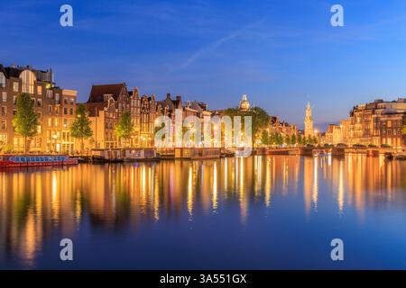 Amsterdam de nuit en Hollande avec des lumières lumineuses de la ville avec ses canaux et ses vieilles maisons de front de mer et ses ponts - une image de voyage Banque D'Images
