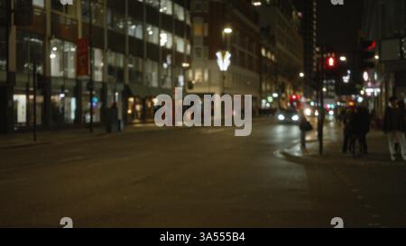 Scène de rue nocturne floue à londres, avec lumières défocalisées, bâtiments et piétons dans un cadre hivernal, évoquant un sentiment de vie nocturne urbaine Banque D'Images