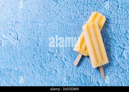 Popsicles jaunes sur fond bleu Banque D'Images