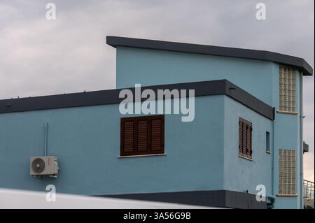 Un bâtiment bleu saisissant se détache sur un ciel sombre, mettant en valeur ses lignes modernes et ses caractéristiques architecturales uniques. Banque D'Images