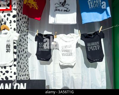 Bébés onesies avec des phrases en dialecte Geordie suspendues sur une ligne de lavage dans un présentoir de magasin Banque D'Images