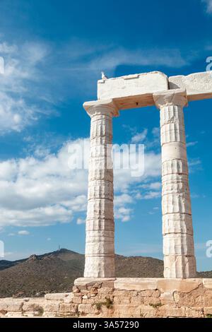Mouette déployant des ailes sur une ancienne ruine de marbre au temple de Poséidon, Sounion, Grèce, soulignant le ciel bleu vif et l'architecture classique Banque D'Images
