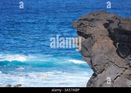 Rocher avec visage en face de la mer bleue Banque D'Images