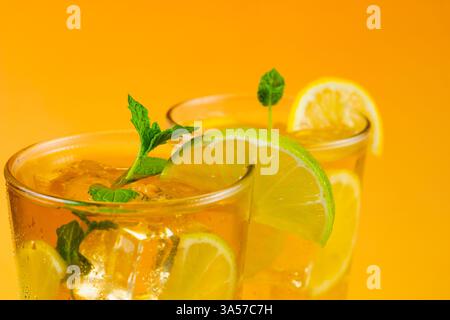 Gros plan de deux verres de thé glacé avec des tranches de citron vert et de citron. La boisson est servie dans un verre avec des feuilles de menthe sur le dessus. Banque D'Images