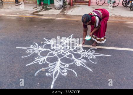 Femme indienne dessinant Kolam Rangoli - forme de peinture dessinée à l'aide de poudre de riz devant la maison Banque D'Images