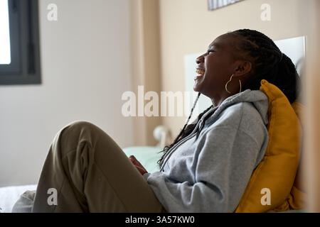 Jeune femme noire riant tout en se relaxant sur le lit Banque D'Images