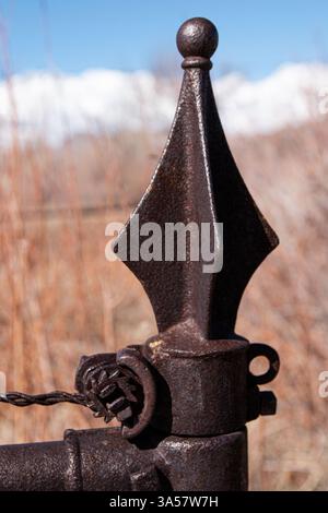 Un finial pointu sur le dessus d'un poteau d'un site funéraire avec un tendeur à cliquet pour serrer le fil de la clôture. Banque D'Images