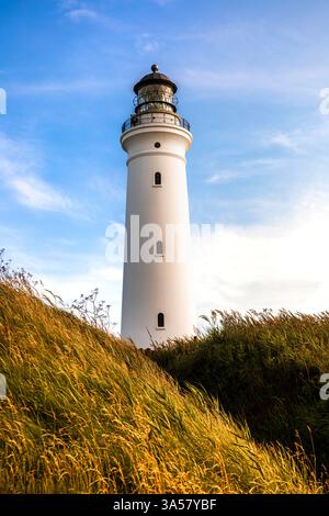 Une vue imprenable sur le phare de Hirtshals pendant le coucher du soleil, sur fond d'un ciel bleu serein et de collines verdoyantes. Banque D'Images