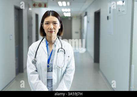 Femme asiatique médecin debout avec confiance dans le couloir de l'hôpital avec stéthoscope Banque D'Images