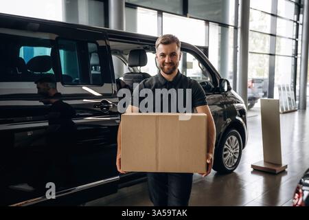 Gros ordre, tenant la boîte. Livreur ou chargeur est près de la voiture avec. Banque D'Images