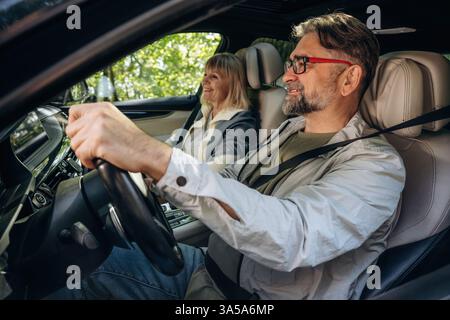 Couple senior conduisant dans la voiture moderne en été. Banque D'Images